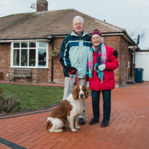 Senior couple with dog in front of house